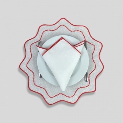 Conjunto de mesa branco com detalhes vermelhos composto por prato, guardanapo e toalha ondulada