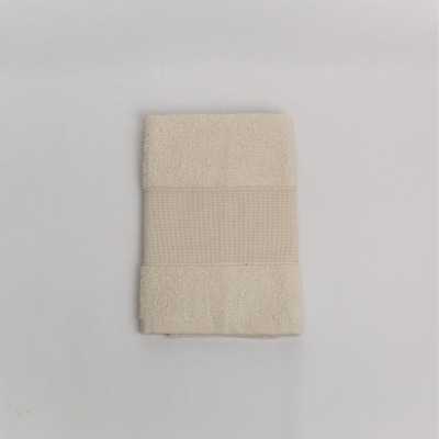 Toalha bege com faixa central texturizada sobre fundo cinza