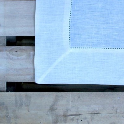 Pano tecido branco com costura decorativa sobre madeira clara