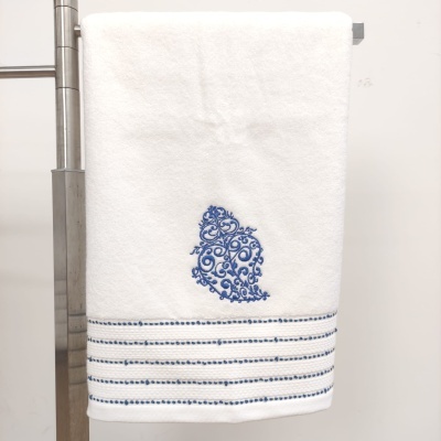 Toalha branca com bordado azul floral e linhas azuis pendurada