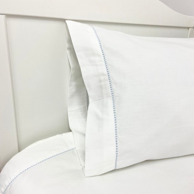 Almofada branca com bordado azul num quarto