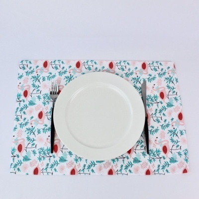 Prato branco sobre descanso de mesa com padrão botânico colorido e talheres