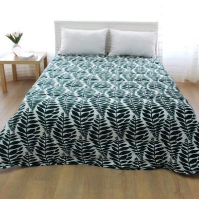 Cama casal com colcha padrão folhas pretas e brancas, duas almofadas brancas.