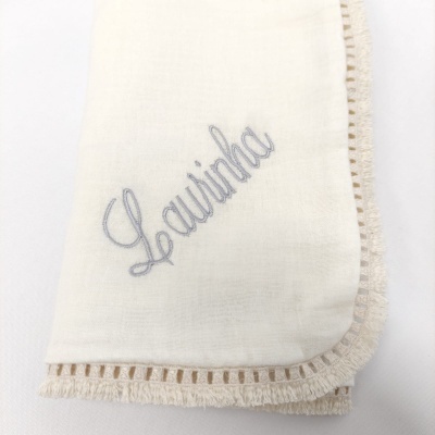 Guardanapo branco com bordado cinza e borda em renda fina.