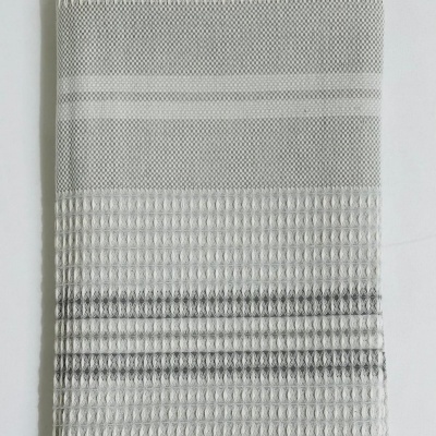 Toalha cinza e branca com padrão de waffle dobrada sobre fundo branco