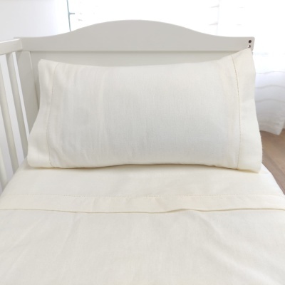 Berço branco com almofada e lençol brancos