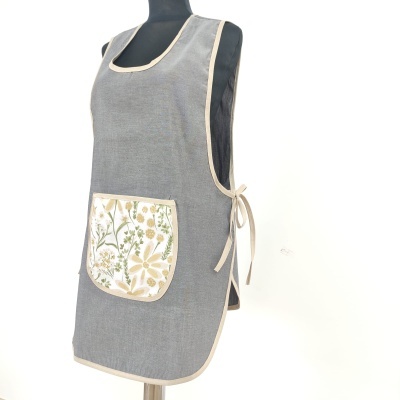 Avental cinzento com bolso floral e acabamento bege num manequim