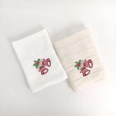Duas toalhas com bordado de sinos vermelhos e folhas verdes, uma branca e outra bege.
