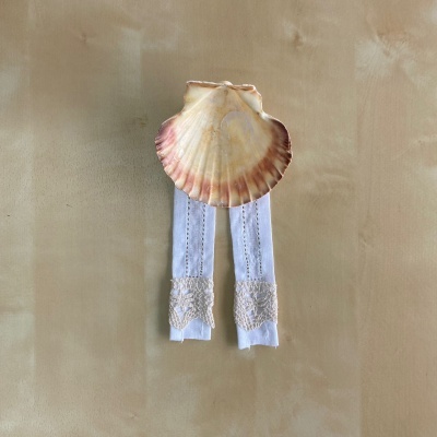 Concha do mar grande com fitas de tecido branco e renda