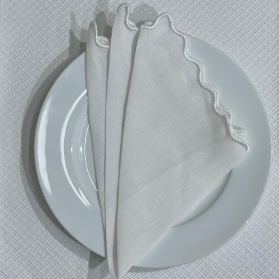 Prato branco com guardanapo branco dobrado em cima sobre toalha de mesa branca texturizada