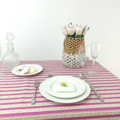 Mesa posta com toalha rosa listrada e jarro com flores cor-de-rosa