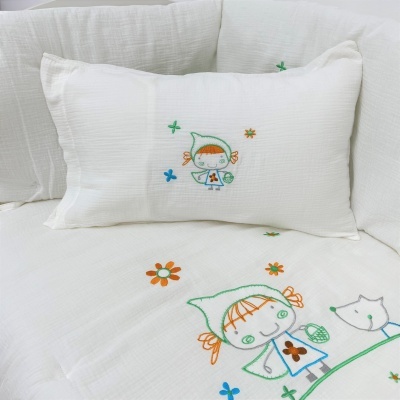 Almofada e colcha brancas com bordados coloridos de crianças, flores e coelho