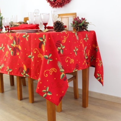Toalha de mesa vermelha com padrão decorativo natalício numa mesa de madeira clara.