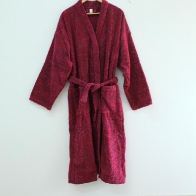 Robe de tecido felpudo vinho com padrão, pendurado num cabide numa parede branca