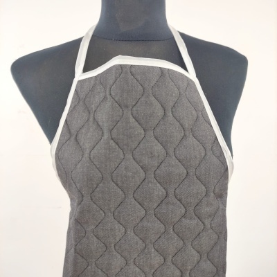 Avental cinza escuro com padrão ondulado em relevo e bordas brancas