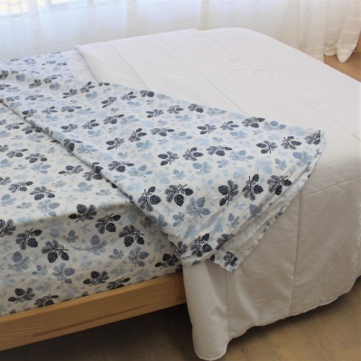 Lençol azul claro com padrão floral azul escuro sobre colchão branco em quarto iluminado naturalmente