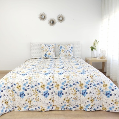 Cama com colcha e fronhas florais azul e amarelo, decoração branca minimalista