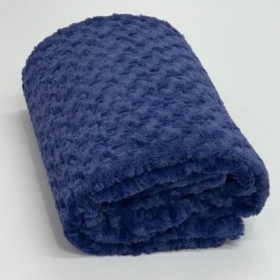 Toalha ou manta azul escuro felpuda com textura bolha dobrada sobre superfície branca