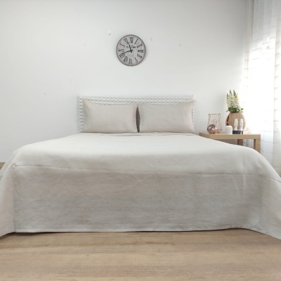 Cama de casal com roupa de cama bege e cabeceira branca ripada em quarto minimalista