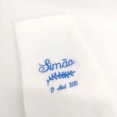 Pano branco com bordado azul do nome Simão, ramo e data 19 abril 2025
