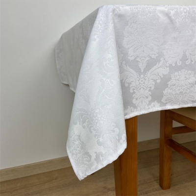 Toalha de mesa branca com padrão floral jacquard sobre mesa de madeira