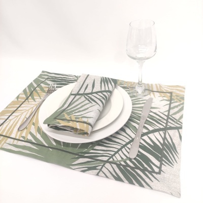 Jogo americano e guardanapo com padrão de folhas, prato branco, talheres e taça de vidro