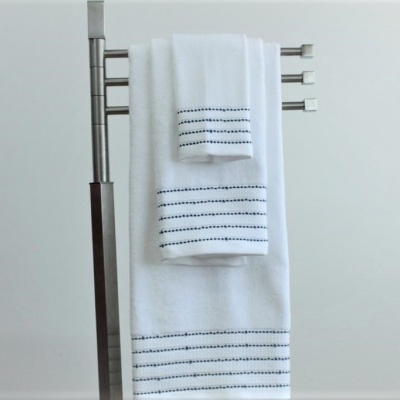 Conjunto de toalhas brancas com riscas pretas penduradas num suporte metálico.