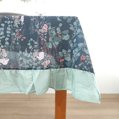 Toalha de mesa floral azul escuro com barra verde clara e mesa de madeira