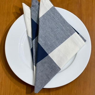 Guardanapo azul, cinza e branco dobrado sobre prato branco