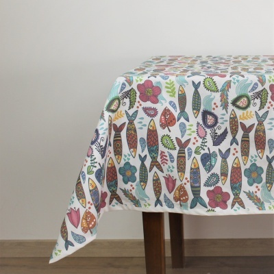 Toalha de mesa colorida com padrão de peixes e flores sobre mesa de madeira