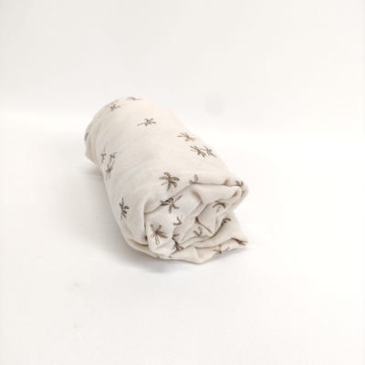 Fralda de pano branca com padrão de insetos castanhos enrolada