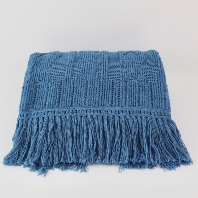 Prenda azul de malha com franjas sobre superfície branca