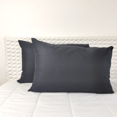 Almofadas pretas sobre cama branca com cabeceira acolchoada