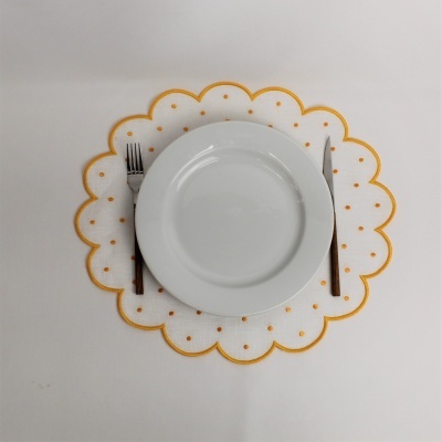 Prato branco sobre sousplat com pontos laranja, garfo e faca com cabo preto