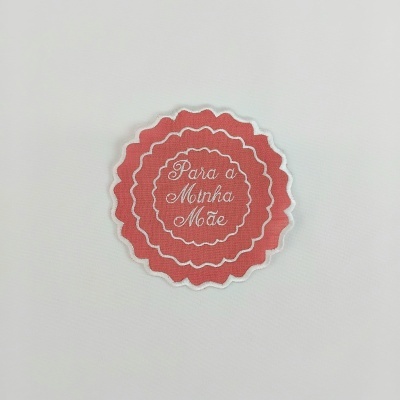 Etiqueta de tecido rosa com texto bordado branco 'Para a Minha Mãe'