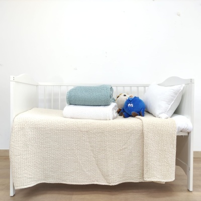 Berço branco com mantas azul e branca, almofada, peluches em fundo branco