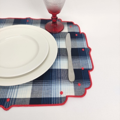 Pito de vidro vermelho, pratos brancos, faca metálica e base de tecido xadrez azul com pontos vermelhos