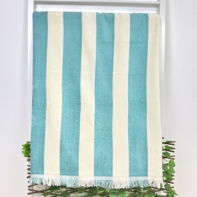 Toalha ou manta com riscas verticais azul claro e creme com franjas brancas na extremidade