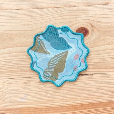 Aplicador de tecido azul com padrão colorido sobre madeira clara