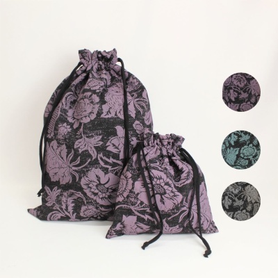 Dois sacos de tecido com padrão floral roxo e preto, com cordões de fecho, fundo branco
