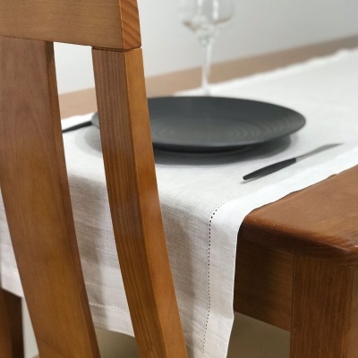 Mesa de madeira com toalha branca, prato preto, copo e faca