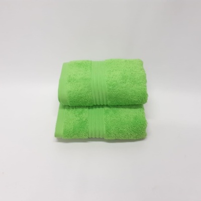 Duas toalhas de banho verdes dobradas sobre fundo branco