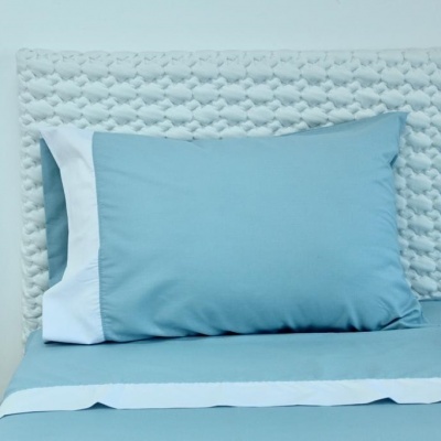 Conjunto de roupa de cama azul claro com detalhes em branco e cabeceira texturizada branca