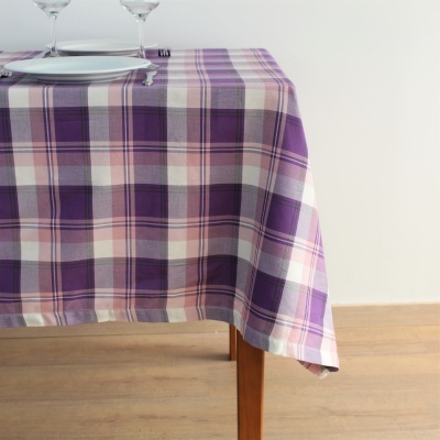 Toalha de mesa xadrez roxa sobre mesa de madeira com pratos e copos
