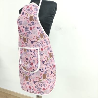 Avental rosa com flores e bolso frontal branco num manequim preto