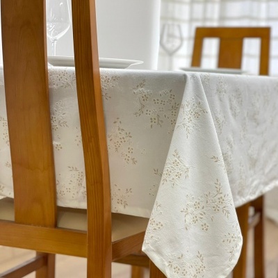 Mesa de madeira com toalha bege com padrão floral e duas cadeiras de madeira.