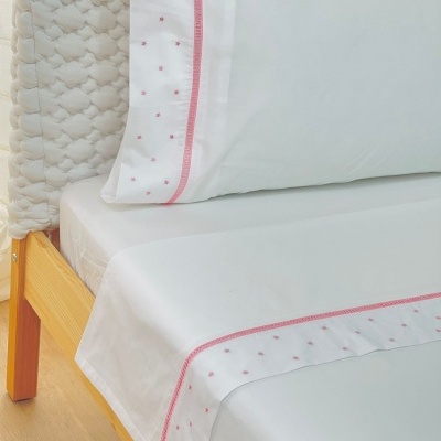 Jogo de cama branco com bordados rosa e cabeceira trançada branca