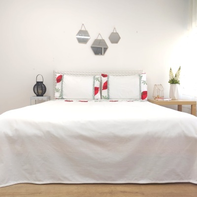 Cama com colcha branca e almofadas decorativas com padrão floral