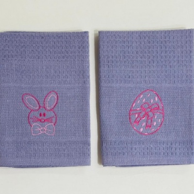 Panos de cozinha azul claro com bordados rosa de coelho e ovo de páscoa