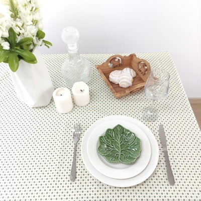 Mesa posta com pratos, talheres, copo, jarra de cristal, velas e flores brancas